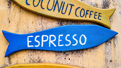 Colorful wooden directional signboards with 'Coconut Coffee' and 'Espresso' painted text, against a...