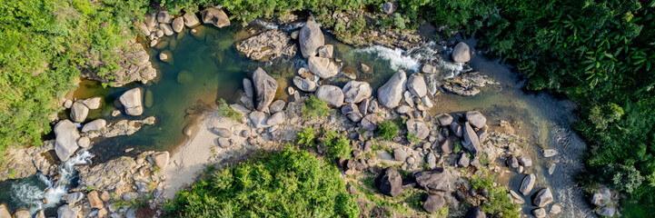 Aerial view of a serene tropical river with clear water flowing through a rocky landscape, surrounded by lush greenery, perfect for nature-themed backgrounds with copy space, Earth day concept