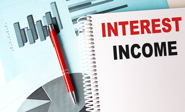 INTEREST INCOME text on a notebook with pen on a chart background