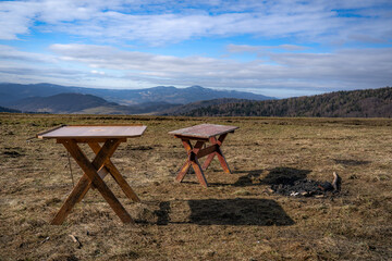 Temporary tables for picnic and bbq in mountains. Wierchomla, Beskid Sadecki in early spring with Radziejowa Range at background.