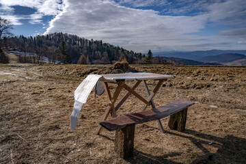 Temporary tables for picnic and bbq in mountains. Wierchomla, Beskid Sadecki in early spring with High Tatras at background.