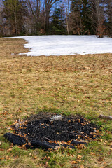Campfire remains on grassfield slope and remains of melting snow
