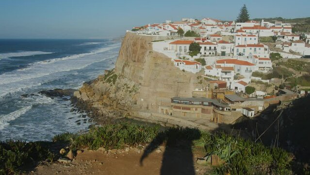 Ocean coast at sunset in Azenhas do Mar, Portugal, Colares area, near Sintra. Azenhas do Mar is a popular tourist destination in Portugal. Beautiful white houses with red roofs are visible.