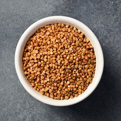 Close-up of buckwheat groats in a bowl. On a dark concrete background.