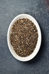 Close up of chia seeds in a ceramic bowl. Superfood On a dark concrete background.