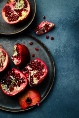 Creative photo, close-up top view of fresh pomegranate pieces on a black stone plate.