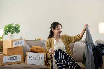 Woman asian holding donation box full with clothes and select clothes. Concept of donation and...