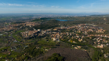 Fototapeta na wymiar Aerial view of Ariccia, in the Metropolitan City of Rome, Italy. The houses of the town are built on the Alban Hills near the Italian capital. In the background there is Lake Albano.