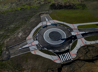 the unfinished development project of a new residential district ends at a roundabout in a field....