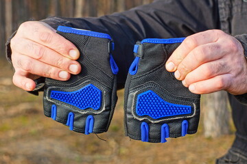 two black nylon protective gloves for cycling and motorcycle riding in the hands of a biker dressed...