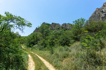 Dirt earthen road to the fortress. The ruins of a medieval castle on top of a huge rock. Stone...