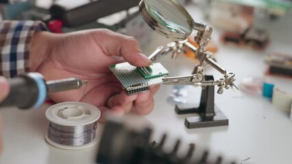 Boy soldering diy fpv drone electronics with soldering iron and magnifying glass