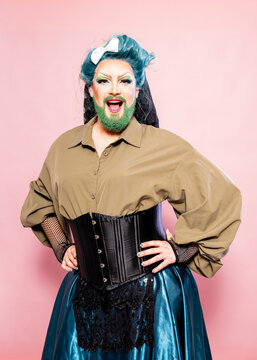 Crossdressing Man Posing Confidently in Corset and Skirt Against Pink Background