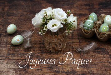 Carte de voeux Joyeuses Pâques : fleurs et œufs de Pâques sur bois rustique décorés de...