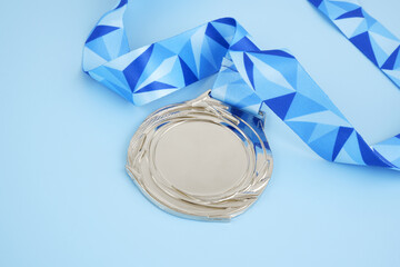 Silver medal with blue ribbon on blue background. 