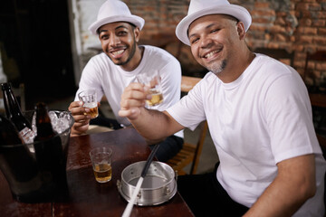 Men, friends and toast with alcohol in portrait at pub for good luck with smile, bonding or party with beer. People, together and happy for bottle, glasses or cheers at social event in Rio de Janeiro