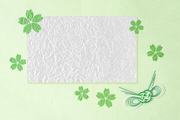 和紙の切り絵風デザインのフレーム　緑の桜の花と水引結び（薄緑の背景）