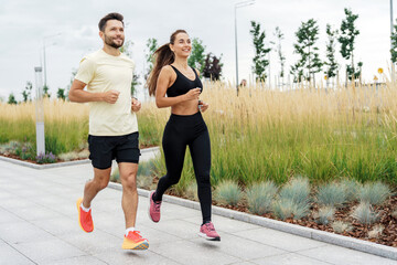 Man and woman in sportswear jogging through an urban park, showcasing teamwork and the joy of shared fitness goals.