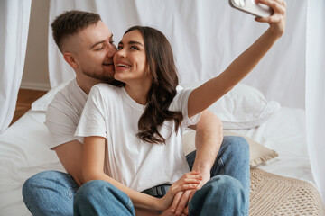 Using smartphone for selfie. Young couple are together at home