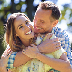 Portrait, embrace and happy couple with smile in park for summer romance, trees and fun outdoor...