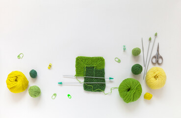 Hand knitting square pattern using 10-stitch method from wool yarn in different shades of green color. Spring crafts and needlework. Flat lay, copy space, top view, close-up, mock up