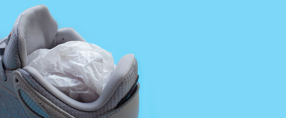 Sneakers with crumpled paper on blue background.