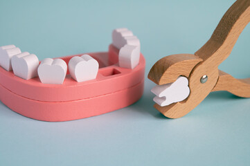 Toy wooden teeth on a turquoise background. Pull or remove tooth medical concept.	Model of a jaw...