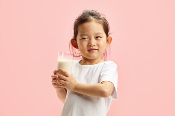 Pretty Child Girl Holding Glass of Milk on Pink Isolated