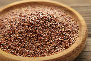 Wooden bowl with flax seeds on grey background.