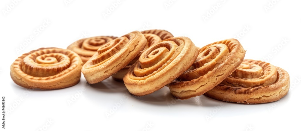 Poster A group of spiral cookies stacked on top of each other on a clean white table surface. The cookies appear freshly baked and are neatly arranged in a pile.