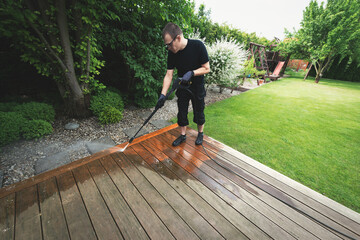 man cleaning terrace with a power washer - high water pressure cleaner on wooden terrace surface - 743695269