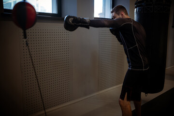 Intense workout of boxer practicing on floor-to-ceiling bag in gym