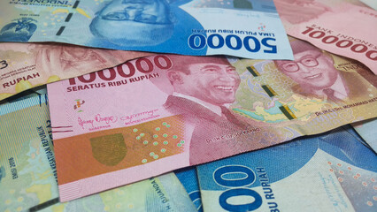 Indonesian currency worth IDR 100,000 and IDR 50,000 fills the frame. Backgrond concept