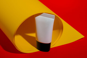 Cosmetic product in tube, bottle, lotion or serum on yellow and red background.