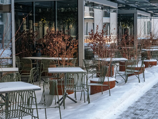Metal outdoor furniture on a snowy summer terrace