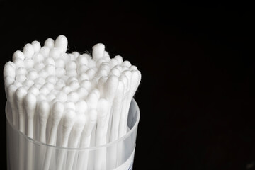 Fototapeta na wymiar Macro view of white cotton ear cleaning buds arranged in black background nicely in a container