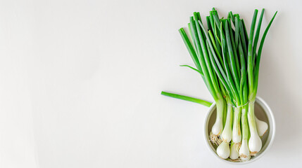 Fresh green onions in a cup on a white background.