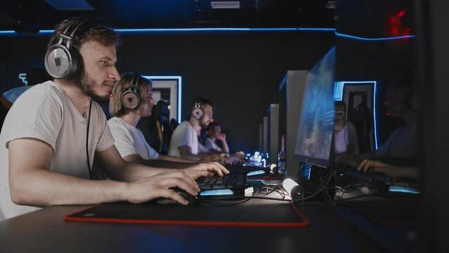 Team of gamers playing video game on PC at computer club, cyber sport tournament. E-sport championship. Five players in headset. Multiplayer online battle competition, real-time strategy RTS