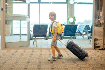 Fototapeta na wymiar Cute blond child, kid with backpack, boarding airplane at the airport on sunset, enjoying the view