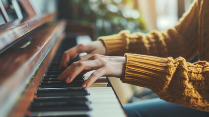 A hands of a young girl in yellow sweater playing the piano