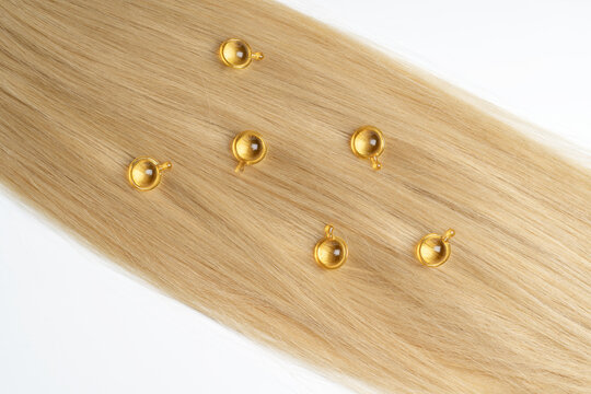 Golden hair serum capsules on blonde strands