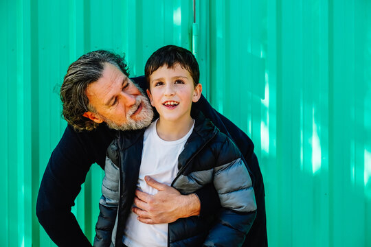 Tender moment between father and son against green background