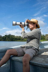Obraz premium Photographer with telephoto lens with hat on a boat