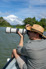 Obraz premium Photographer with telephoto lens with hat on a boat