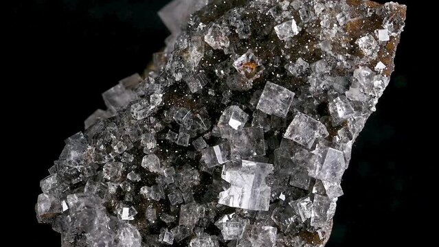 Fluorite crystals on am matrix, sample rotating slowly against a black background.	