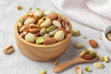 Nuts mixed in wood bowl on linen cloth
