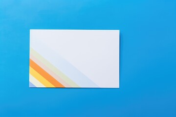 LGBT Pride Flag with Blank Card. A rainbow LGBT pride flag lies beside a blank card on a blue background, symbolizing openness and identity.