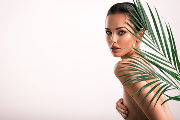 Young beautiful woman with green leaves near naked body. Body care beauty treatments concept. ...