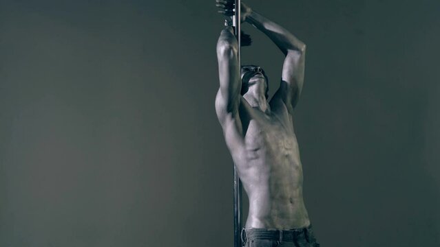 Sexy man pole dancer. Guy does gymnastic exercises on pole dance. Pole dancing for slim fitness body. Flexibility. Pole dance. Pylon dancing strength, flexibility, and grace. Strip dancer.