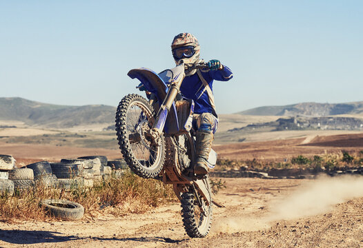 Motorcycle, action and balance of person with speed and skill for adrenaline and stunt with extreme sports outdoor. Competition, adventure and power with risk, biker riding on motorbike with wheelie